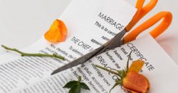 A marriage certificate paper being cut in two by scissors