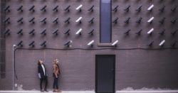 Two women facing security camera above mounted on structure