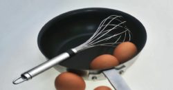 whisk on saucepan with organic eggs