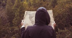 person facing forest reading world map