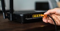 A hand plugging a wire into a network router