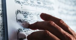 person reading musical sheet tracing the notes with the fingers