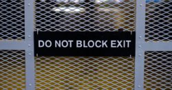 "Do not block exit" sign on a mesh metal fence