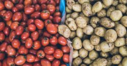 A box half filled with tomatoes and another half - with potatoes