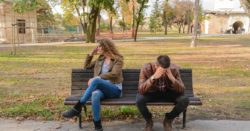 Two people on a bench in a disagreement as indicated by the body language