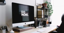 Monitor on a busy desk with the words "Do More" on the screen