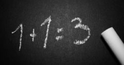 1 + 1 = 3 equation written in chalk on blackboard