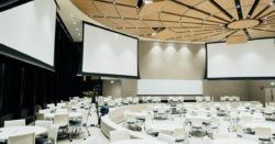 Empty event room with tables, screens, and projectors